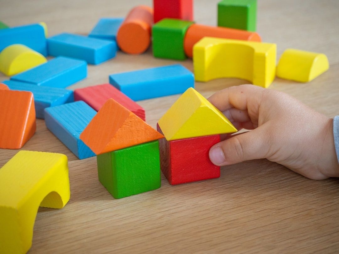 Hand bouwt met kleurrijke houten blokken een klein huisje