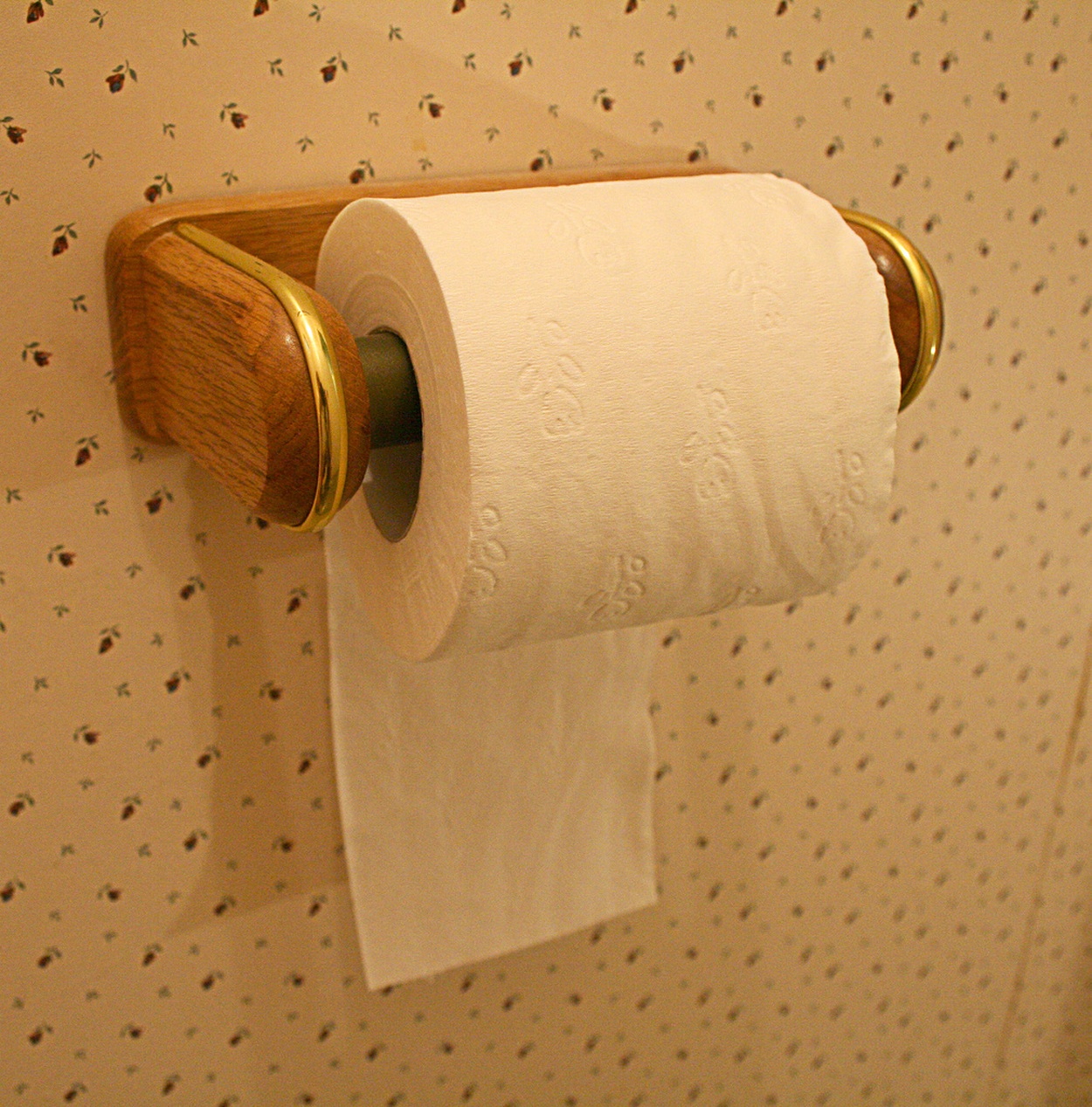 Een close-up van een moderne zwarte toiletrolhouder met een handig plankje waarop een smartphone ligt.